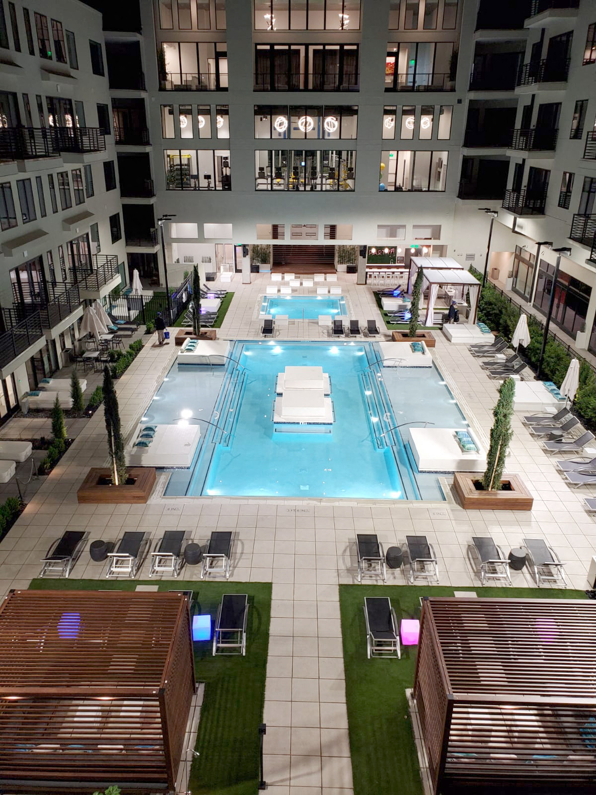 A large swimming pool surrounded by lounge chairs and potted plants.