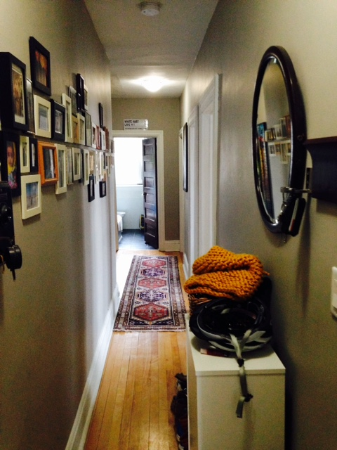 a hallway with a mirror and a dresser and a rug