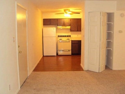 an empty kitchen with a white refrigerator and a door