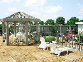 a wooden deck with white chairs and a gazebo