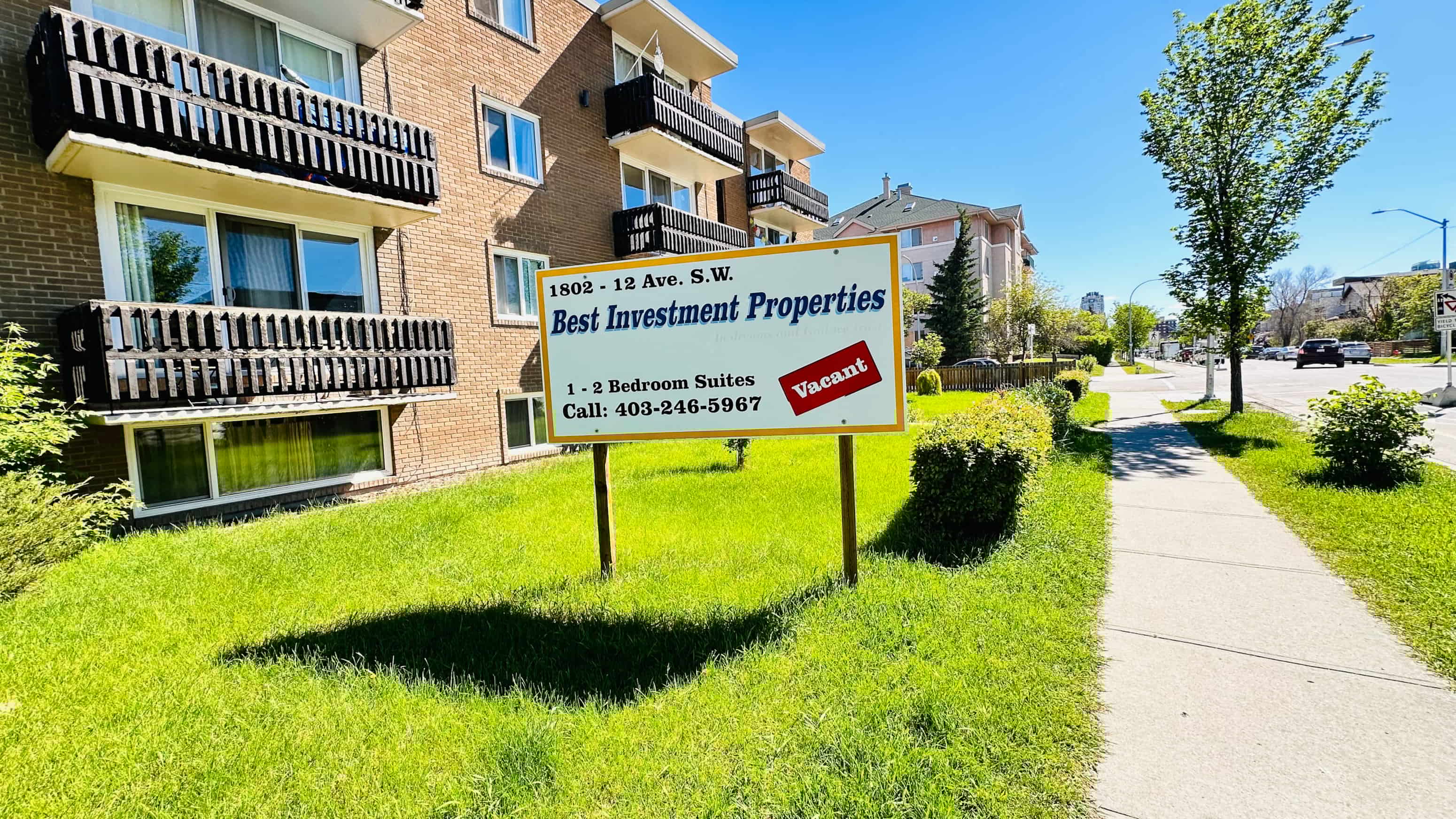 a sign in the grass in front of an apartment building