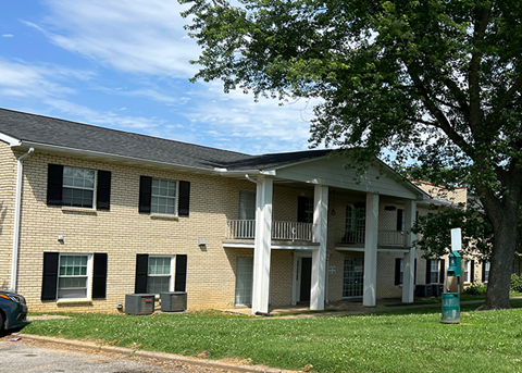 Brick apartment building with columns and green space