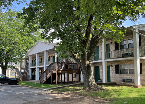 Two-story apartment building with outdoor stairs and shade trees