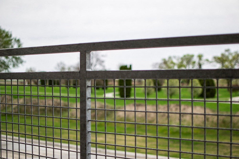 a fence with a grass field in the background