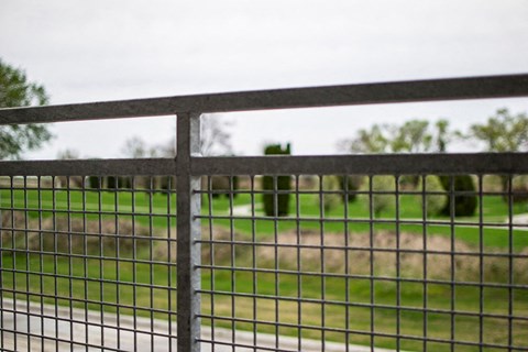 a fence with a grass field in the background