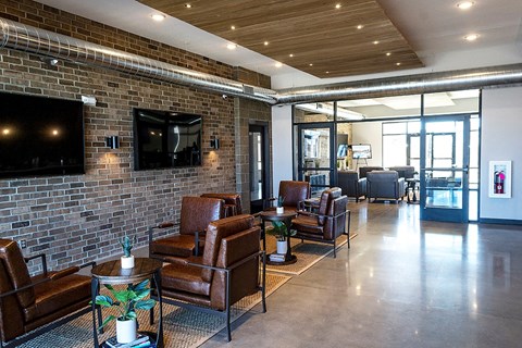 a lobby with leather furniture and a brick wall with a television