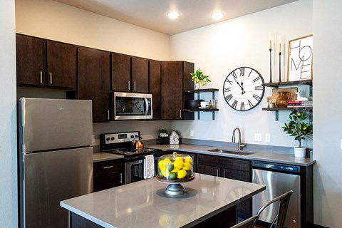 a kitchen with stainless steel appliances and a clock on the wall