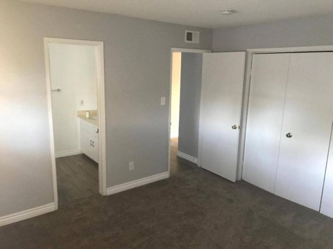 a bedroom with white closets and a carpeted floor