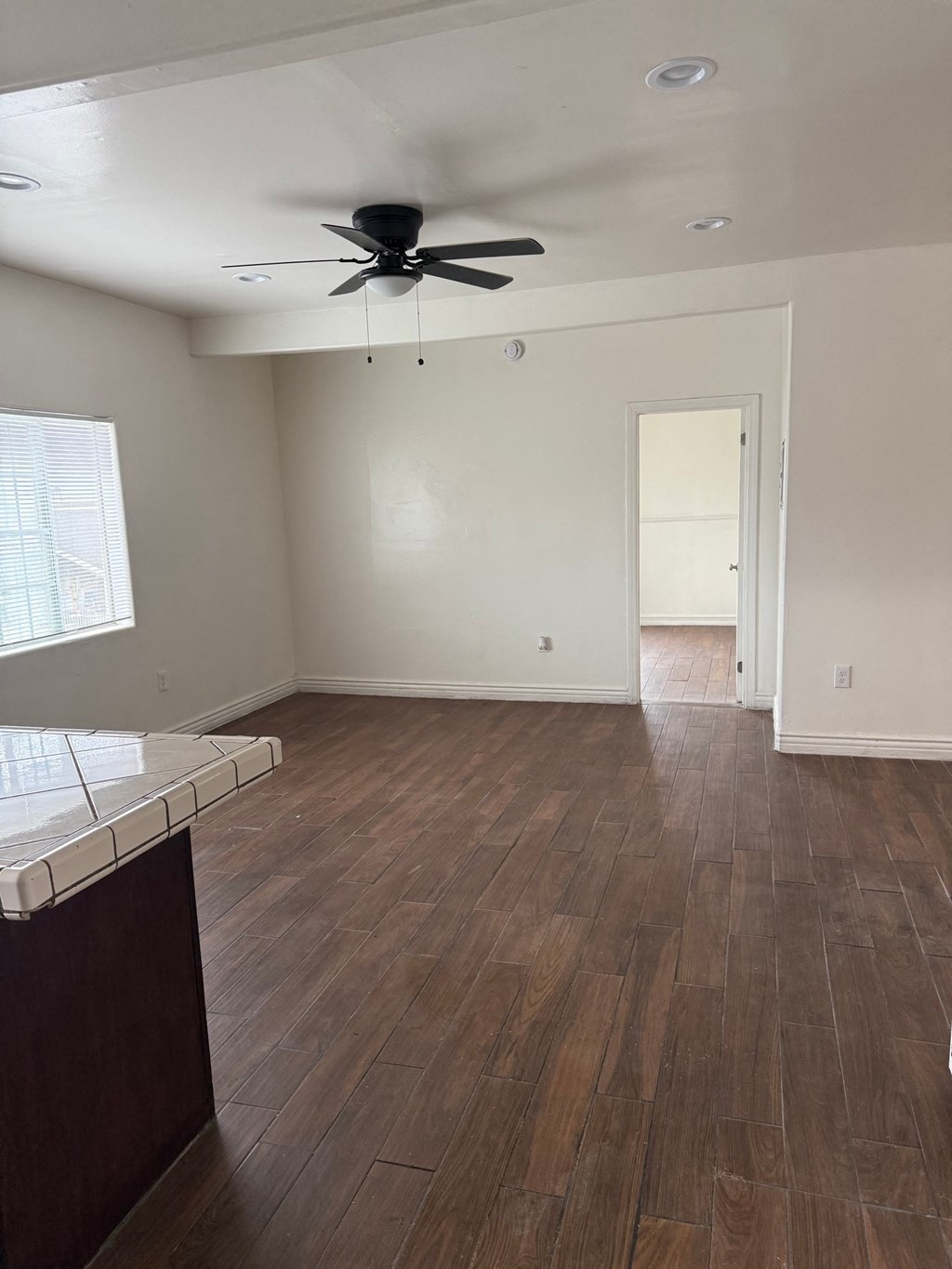 A room with a ceiling fan and wooden flooring.