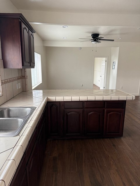 A kitchen with dark wood cabinets and a white countertop.