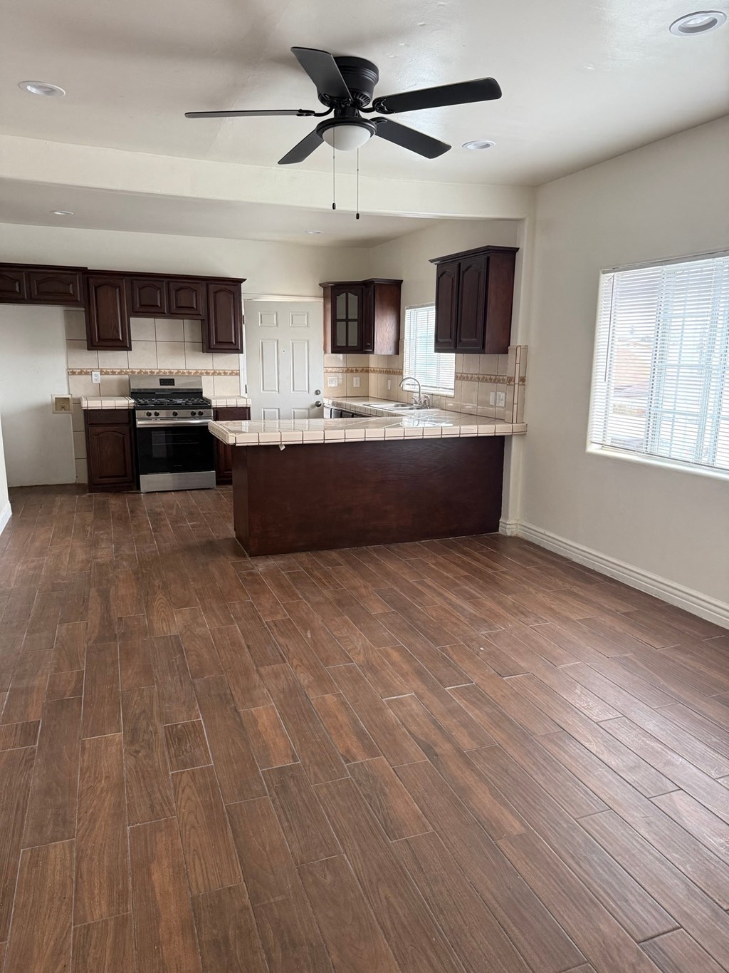 A kitchen with wooden floors and a ceiling fan.