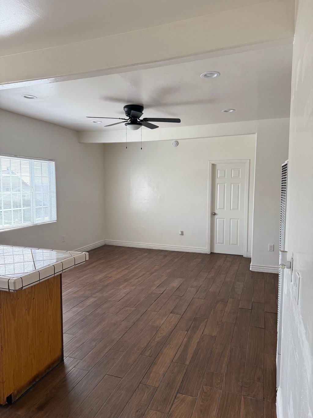 A room with a ceiling fan and wooden flooring.