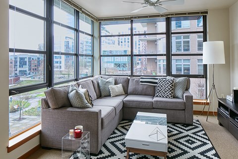 a living room with a couch and a coffee table and large windows
