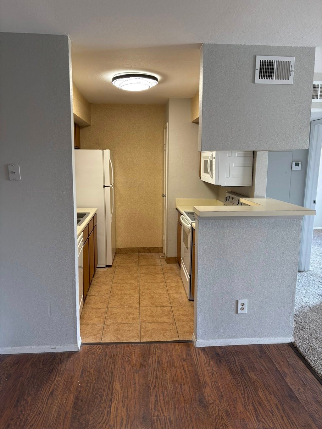 A kitchen with a white refrigerator and wooden floors.
