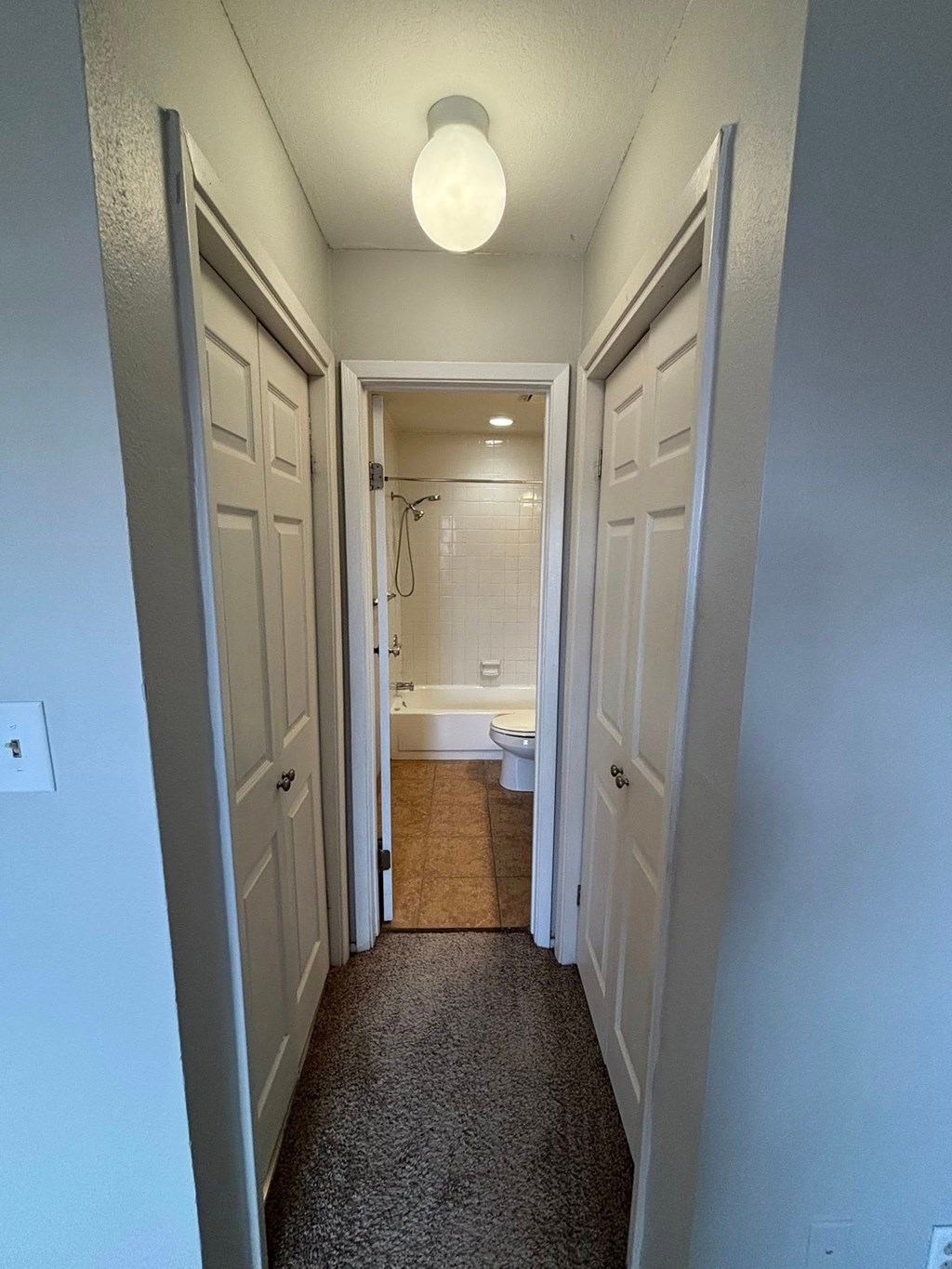 A hallway with a toilet visible in the distance.