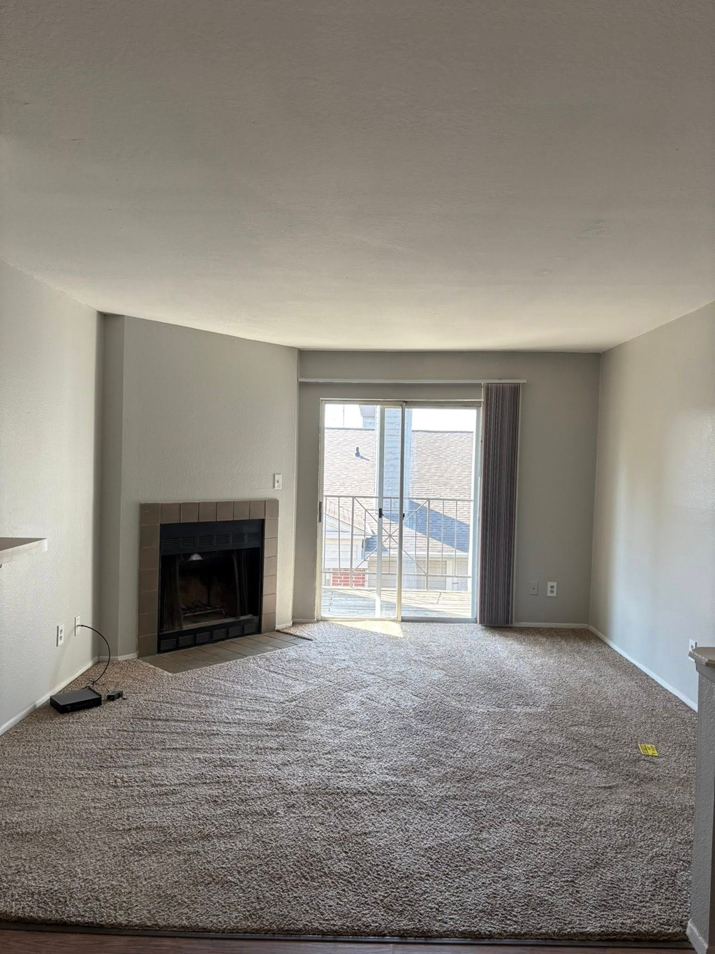A living room with a fireplace and a carpet on the floor.
