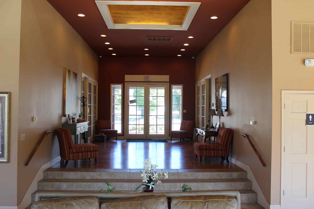 A hallway with a staircase and a door at the end.