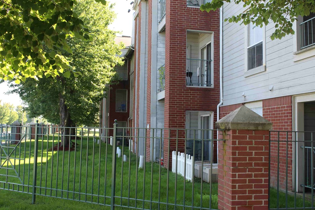 A white house with a red brick pillar in front of it.