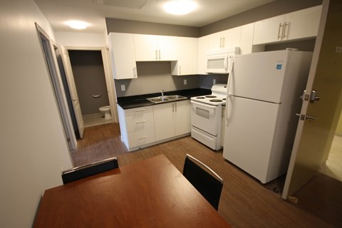 a kitchen with white appliances and a wooden table