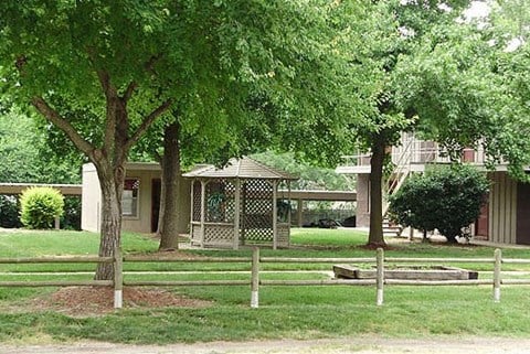 a fenced in area with trees and a house