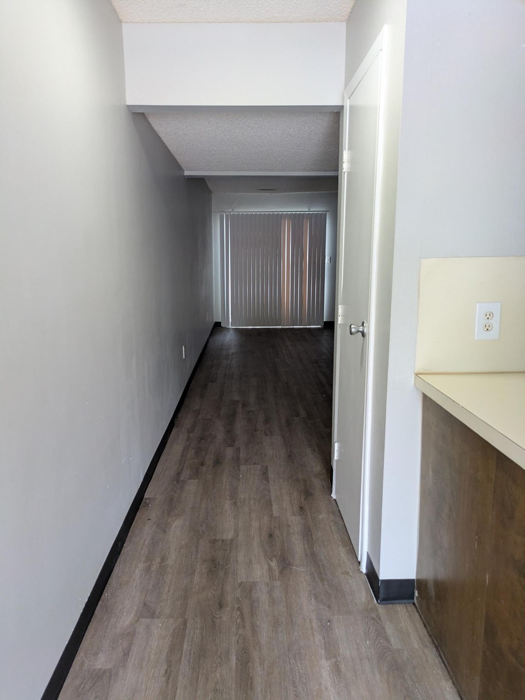 A long hallway with wood flooring and white walls.