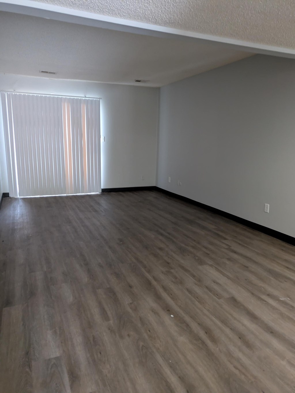 A room with wooden flooring and a window with blinds.