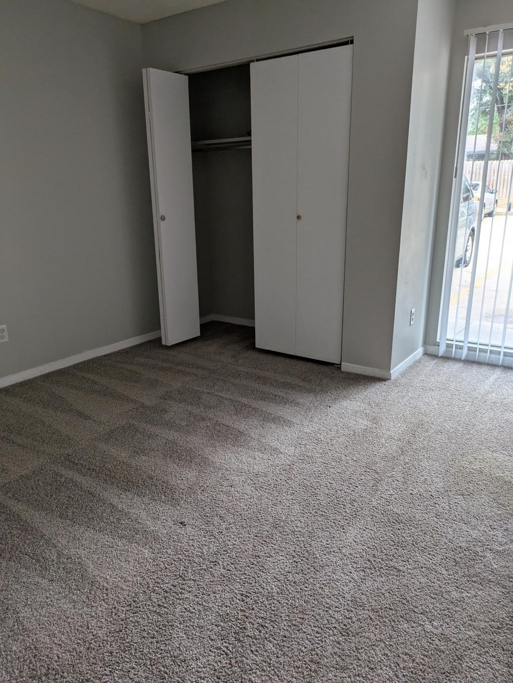 A room with a carpeted floor and a white closet with a door open.