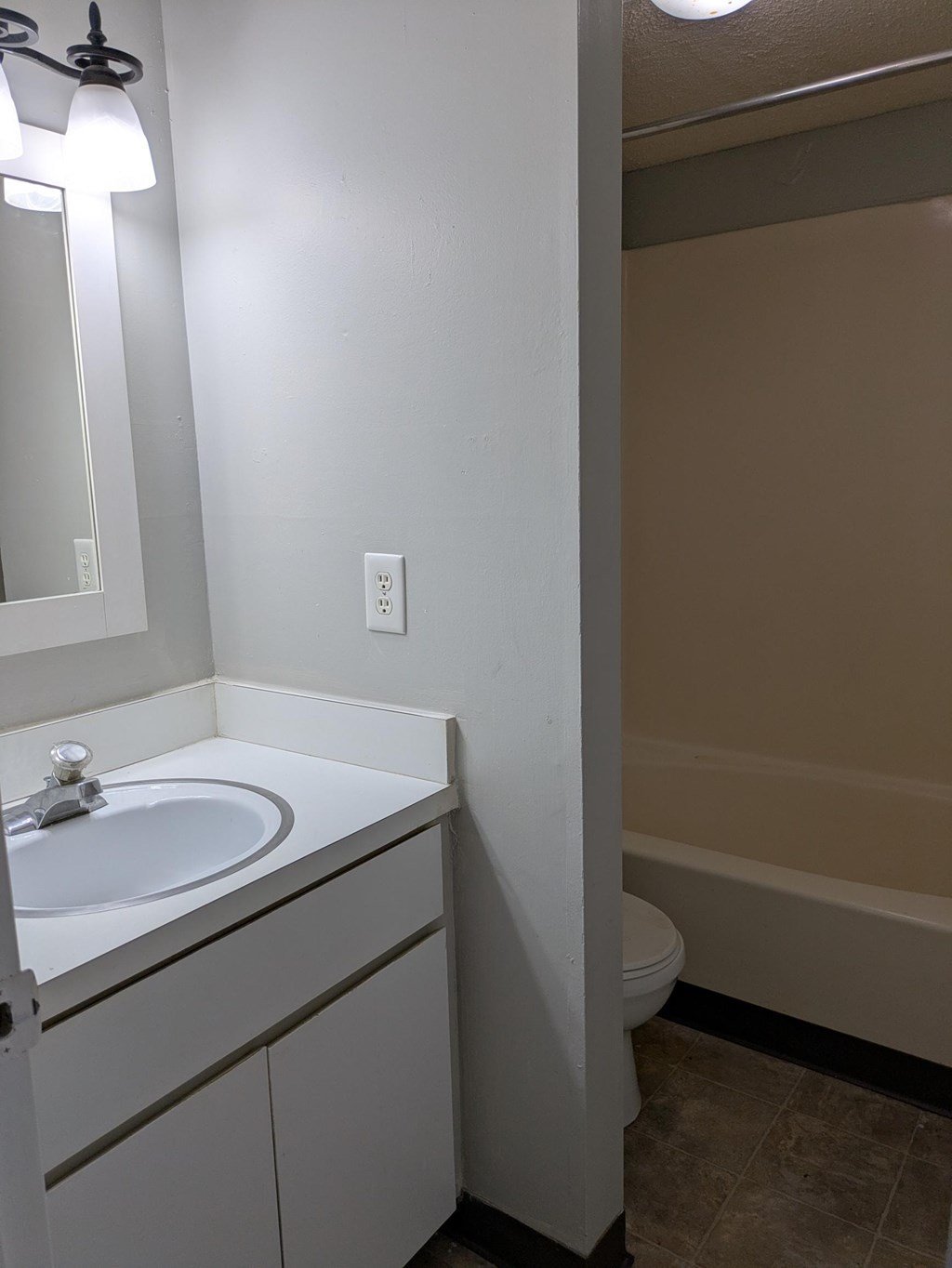 A white bathroom with a sink, mirror, and toilet.