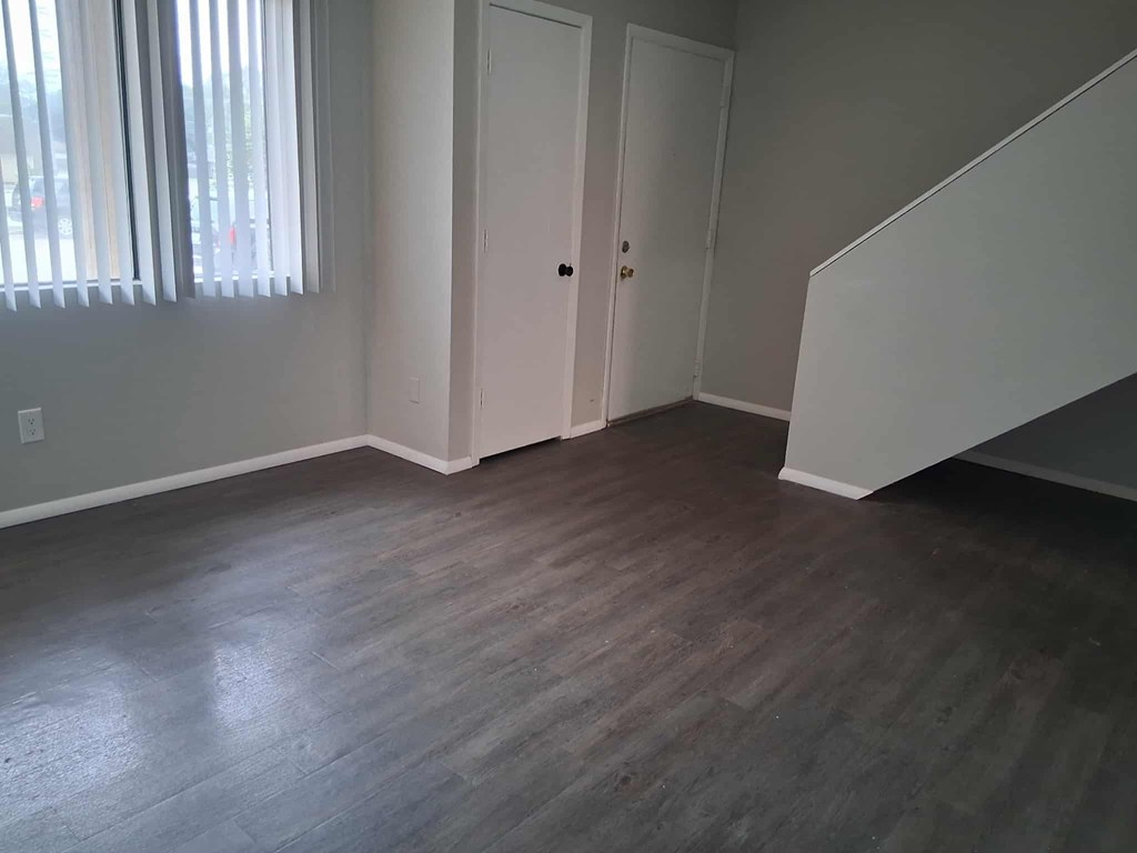 A room with a wooden floor and a staircase.