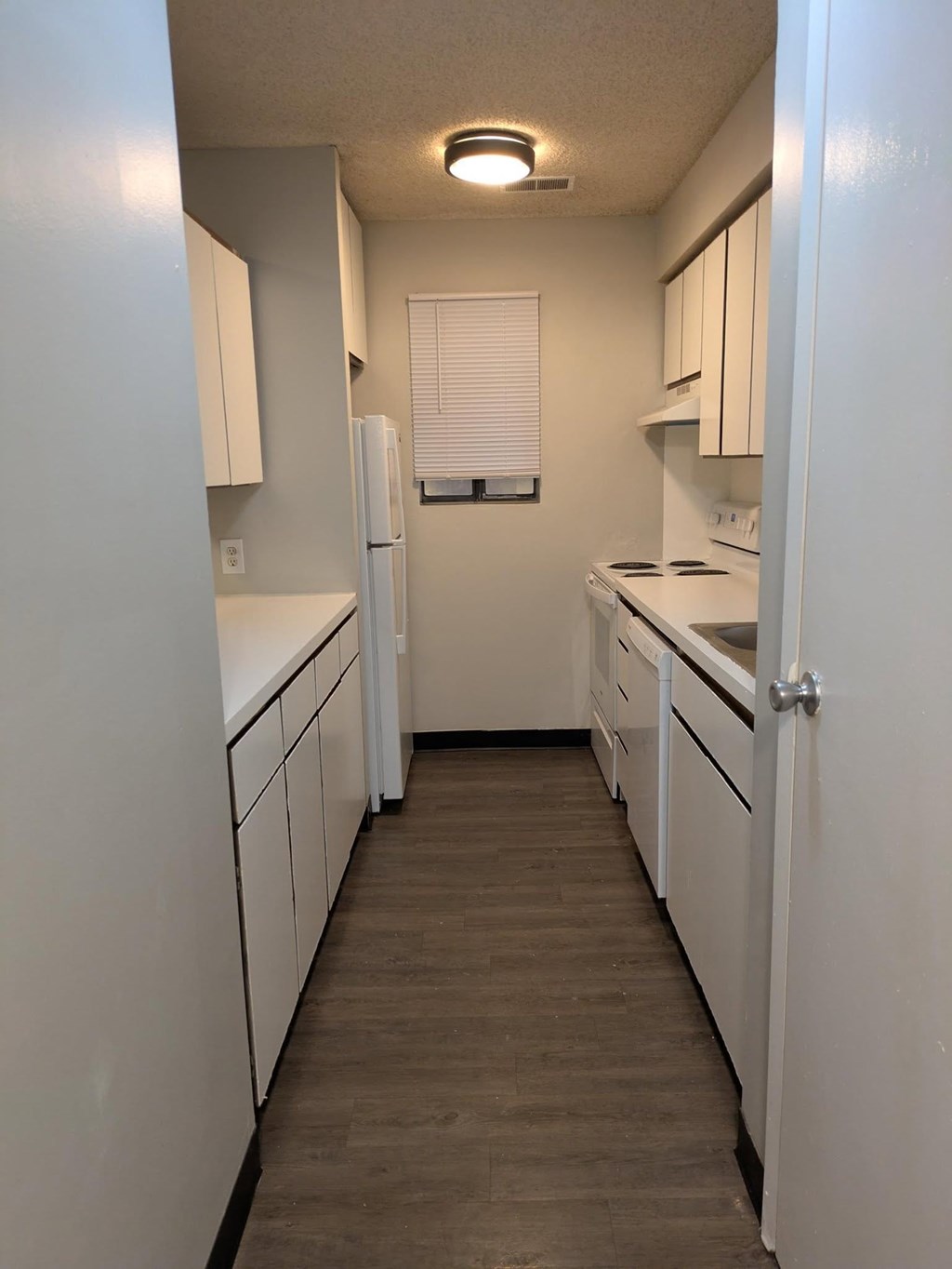 A kitchen with white cabinets and a white refrigerator.