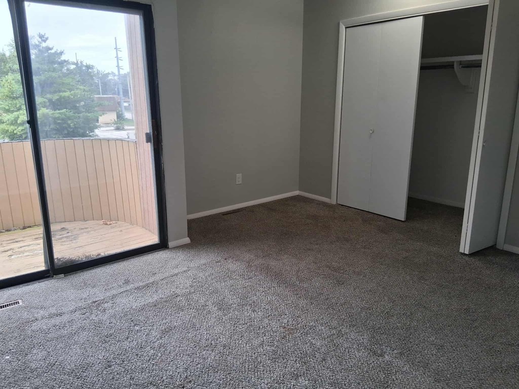 A room with a grey carpet and a white door.