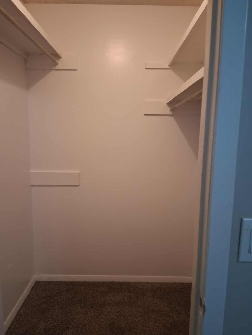 A small, empty room with a carpeted floor and a door on the right.