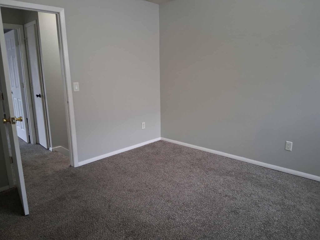 A room with grey carpet and white walls.