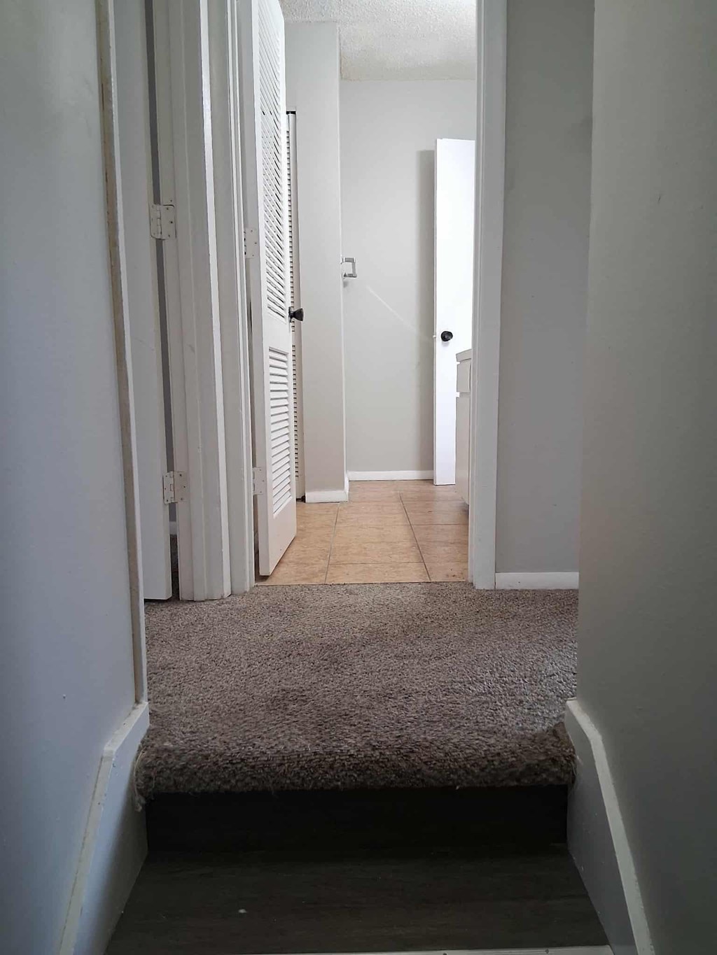A hallway with a carpeted floor and white walls.