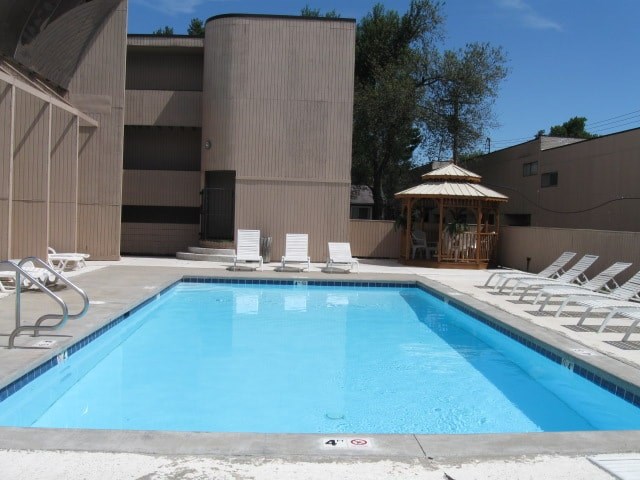 A pool with a gazebo and sun loungers.