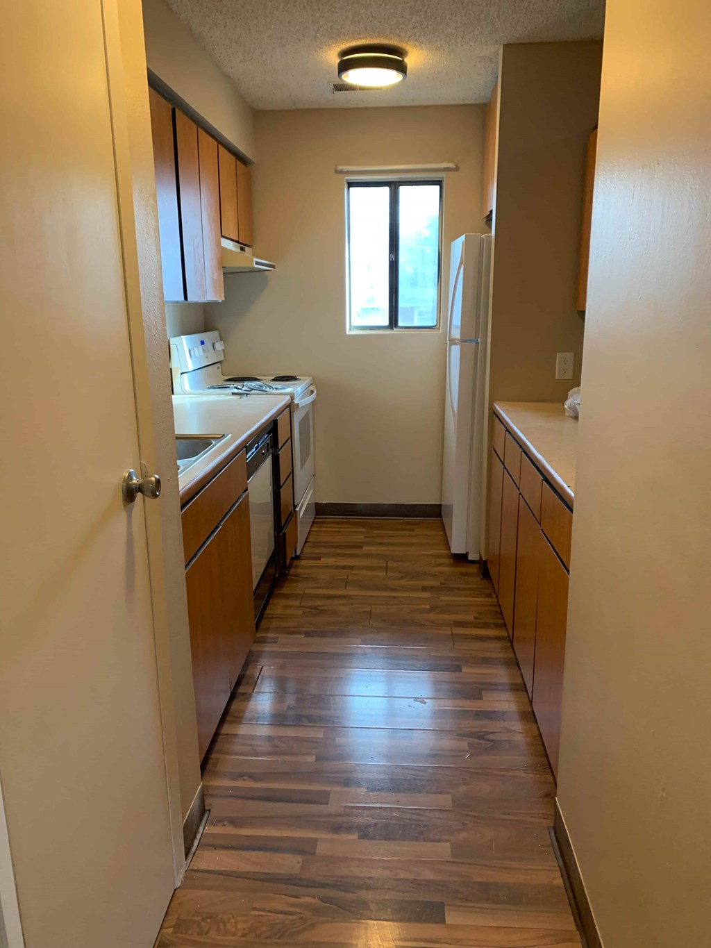 A kitchen with wooden floors and white appliances.