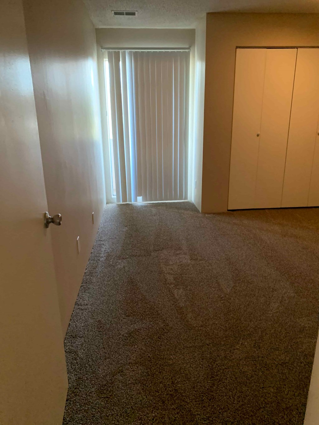 A hallway with a carpeted floor and two doors.