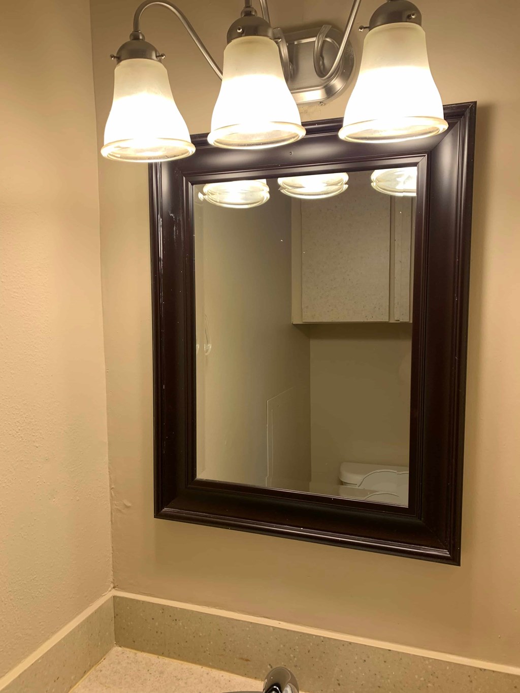 A bathroom with a mirror and lights above it.