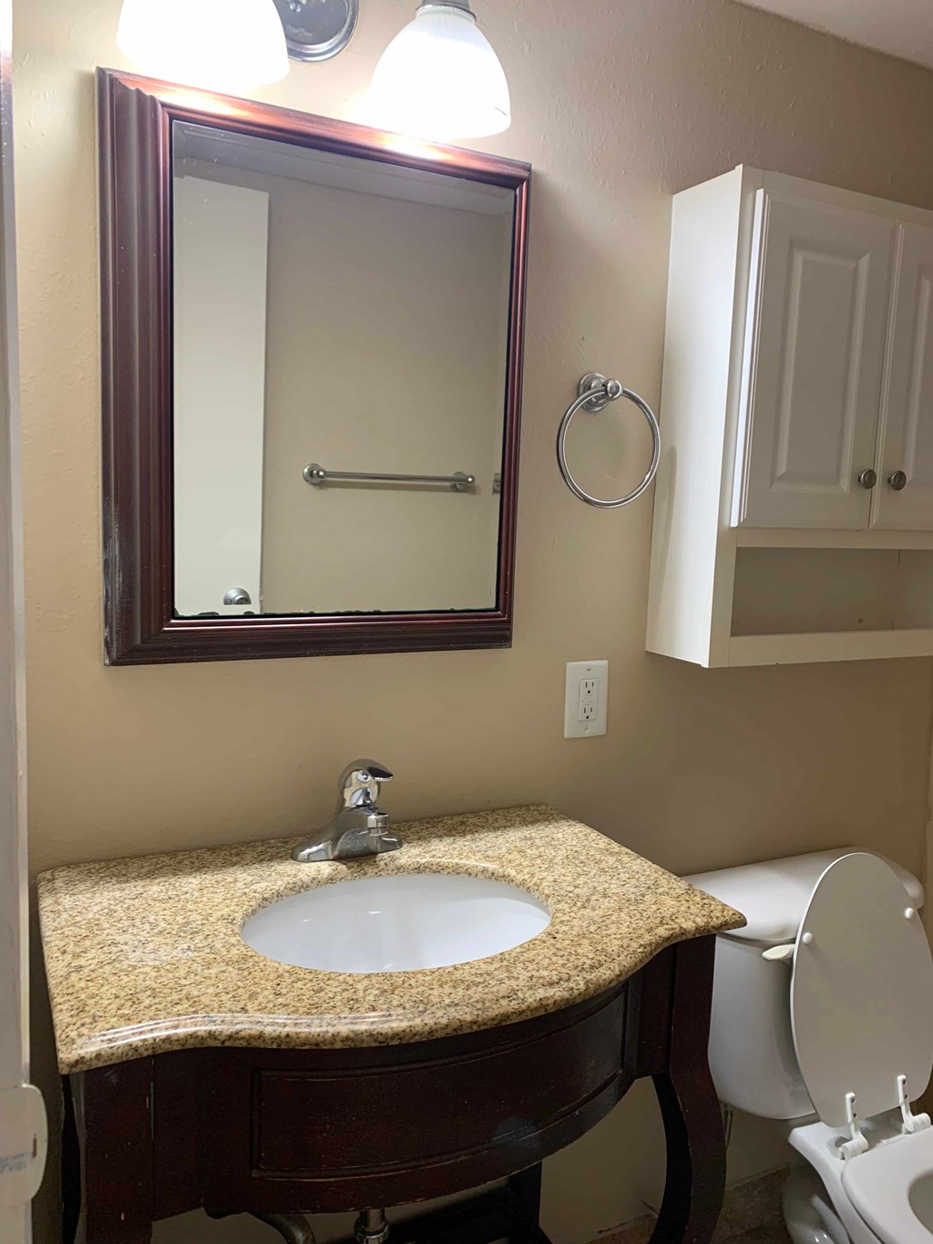 A bathroom with a sink, toilet and mirror.