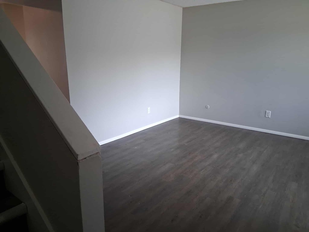 A room with wooden flooring and white walls.