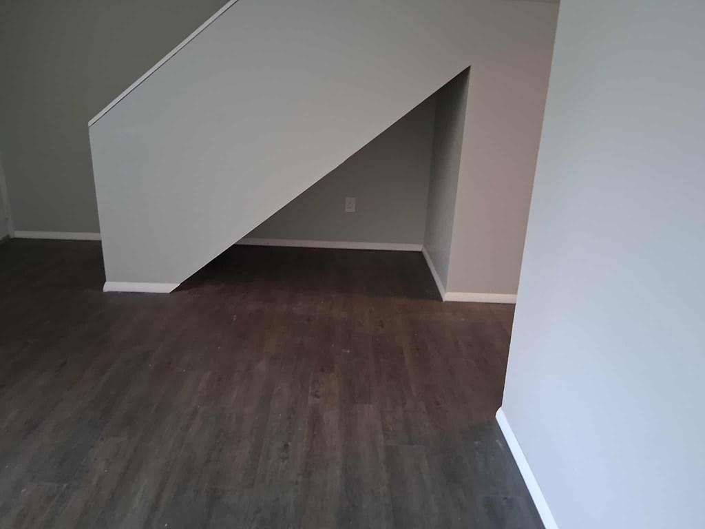 A corner of a room with a wooden floor and white walls.