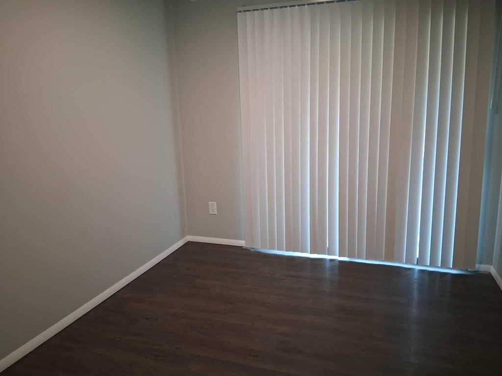 A room with a window covered by white blinds.