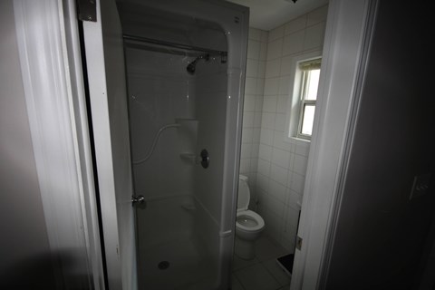 A bathroom with a toilet, a shower, and a window.