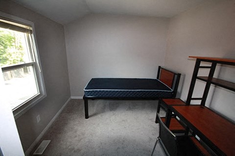 A bedroom with a bed, desk, and chair.