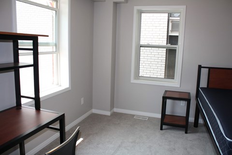 A bedroom with a bed, chair, and a table.