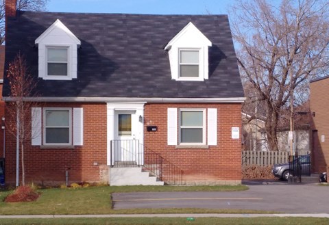 A red brick house with a black roof and white trim.