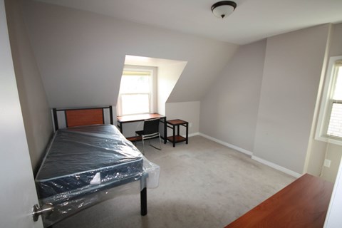 A bedroom with a bed, desk, and chair.