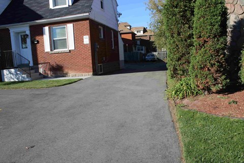 A residential street with a brick house and a tree.