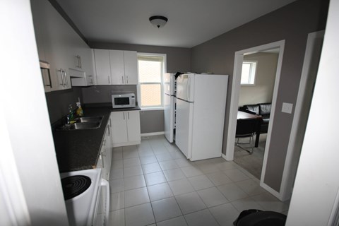 A kitchen with a white refrigerator and black countertops.