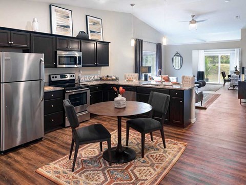 a kitchen with black cabinets and stainless steel appliances and a table